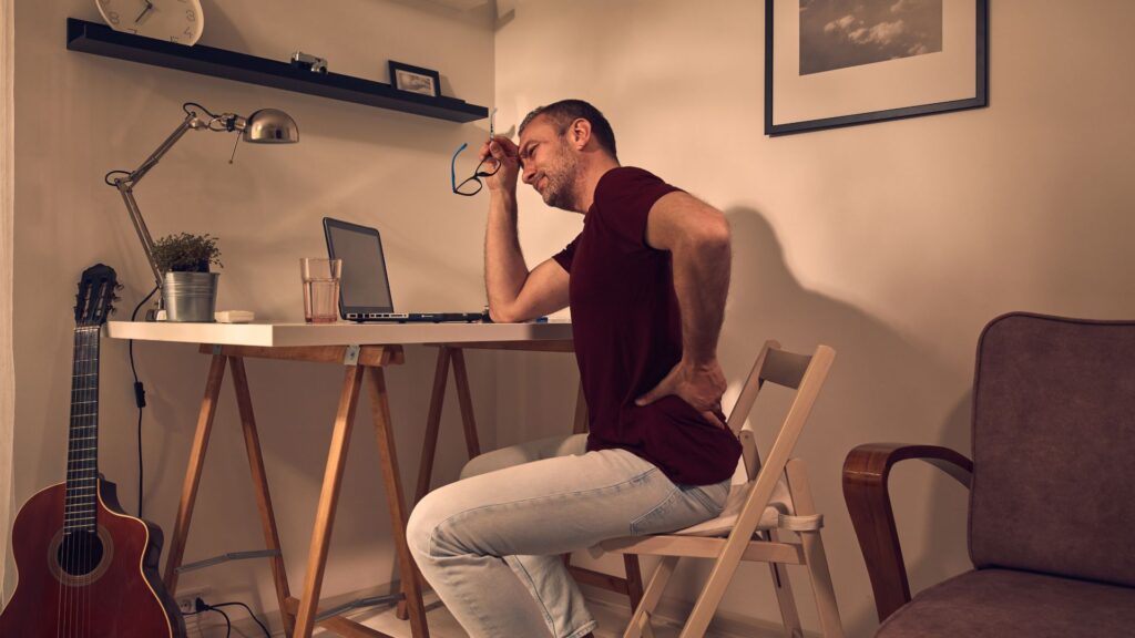 Man sitting at a desk experiencing back pain