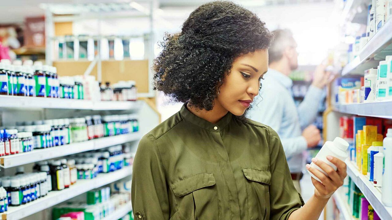 woman in a pharmacy reading the label on a bottle